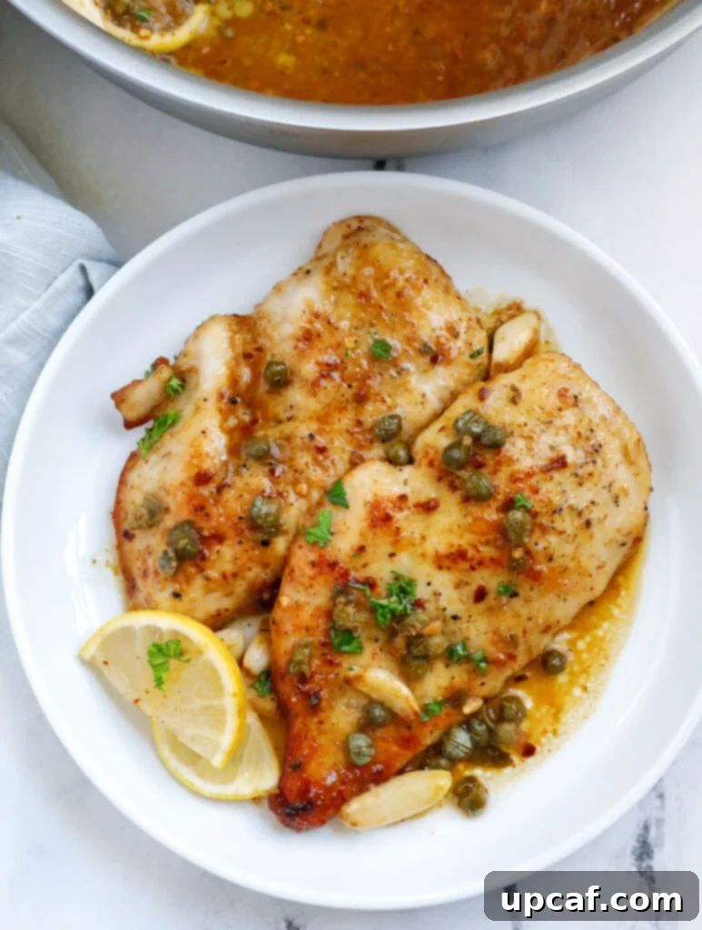 Two perfectly seared lemon chicken piccata cutlets resting on a white plate, ready to be served.