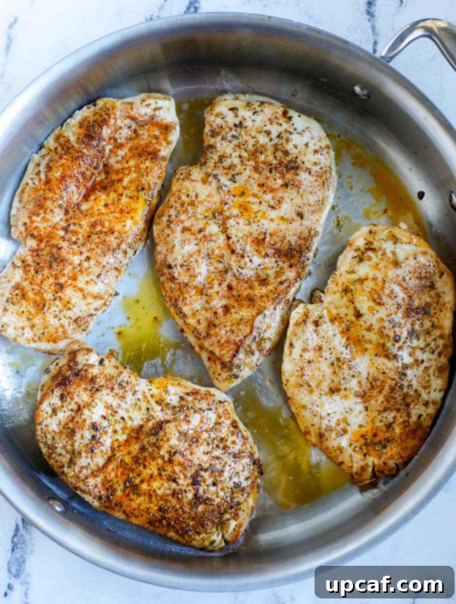 Top down shot of chicken breasts searing in a skillet.
