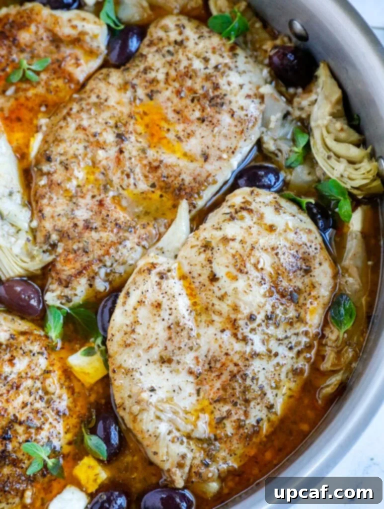 Overhead shot of Greek chicken in a skillet with olives and artichokes, ready to serve.