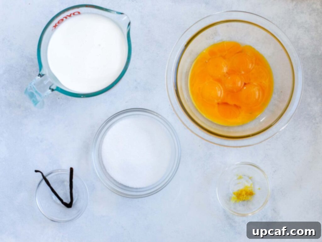 Effortless Crème Brûlée 3 A close-up, top-down view of the ingredients laid out for making crème brûlée: fresh egg yolks, heavy cream, a vanilla bean, granulated sugar, and lemon zest.