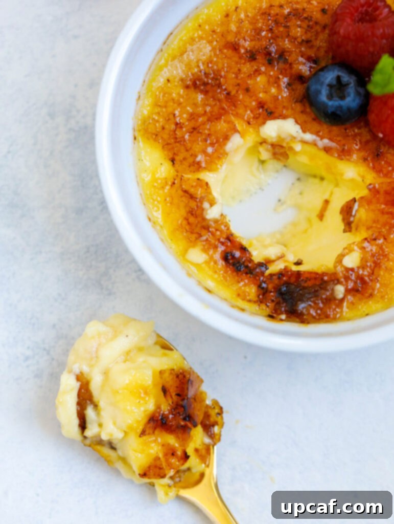 Effortless Crème Brûlée 10 A perfectly torched crème brûlée with a spoonful taken out, revealing the creamy custard and the crisp caramel layer.