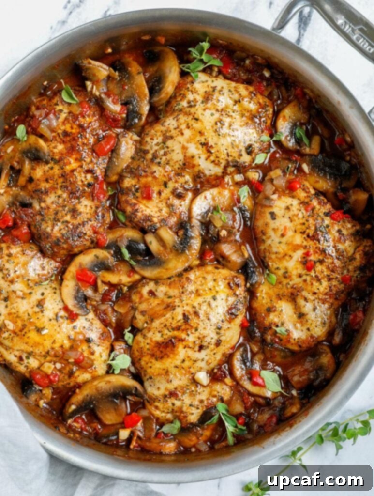 Creamy Tuscan Chicken Thighs 8 Overhead view of Tuscan Chicken in a pan, garnished with fresh herbs.