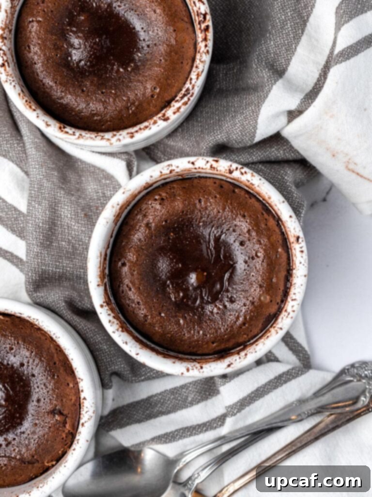 Overhead photo of three freshly baked molten chocolate lava cakes still in their ramekins, cooling slightly.