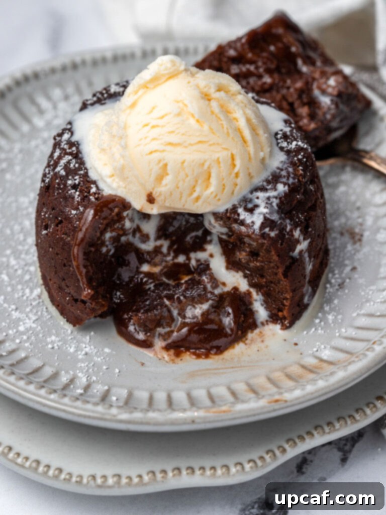 A molten chocolate lava cake with a scoop of ice cream on top, and a spoon digging into its soft, gooey center.