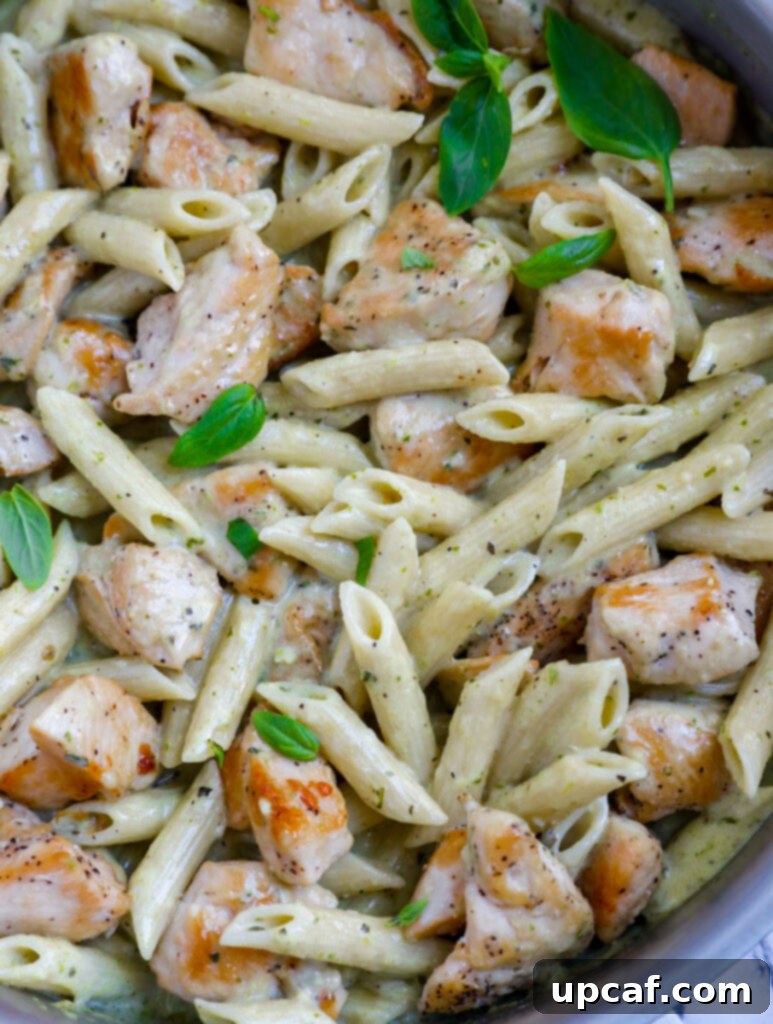A close-up shot of the creamy pesto chicken pasta in a pan, showcasing its rich texture and green sauce, ready to be served.