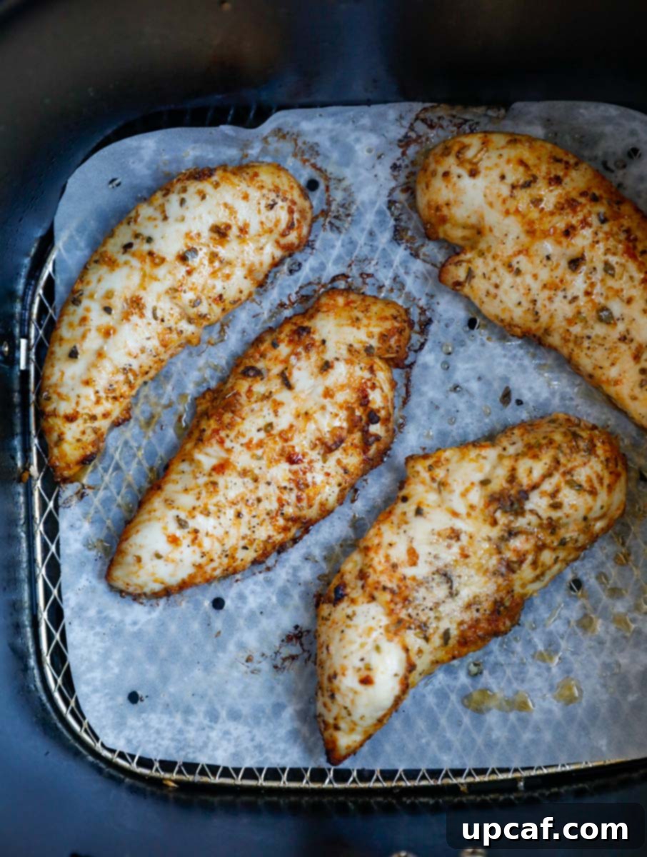 Golden-brown, cooked lemon pepper chicken tenders resting in the air fryer basket, showing a perfectly crispy finish.