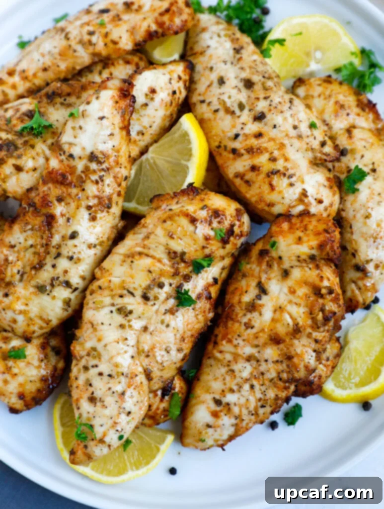 Top down shot of crispy lemon pepper chicken on a white plate, garnished with fresh parsley and bright lemon wedges, ready to be served.