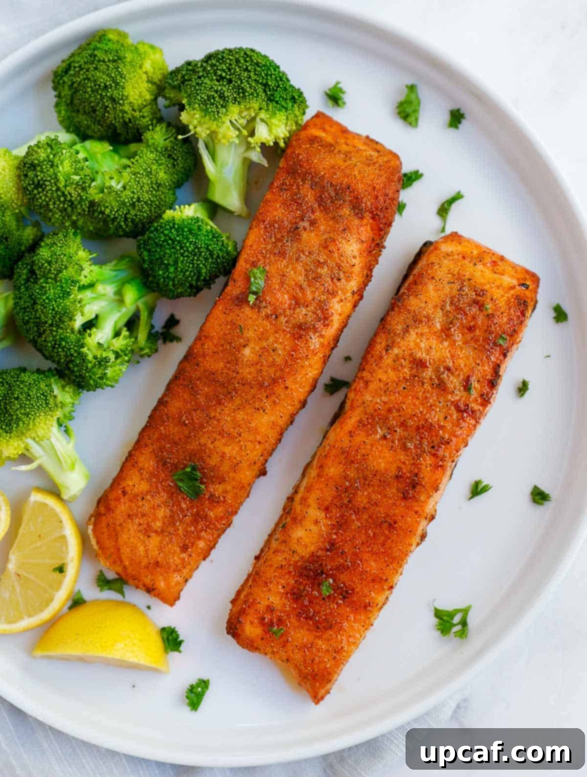two pieces of air fried salmon on a plate with broccoli