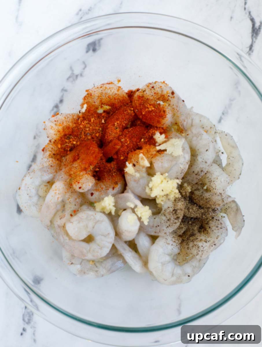 Raw shrimp and seasoning in a bowl, ready for mixing.