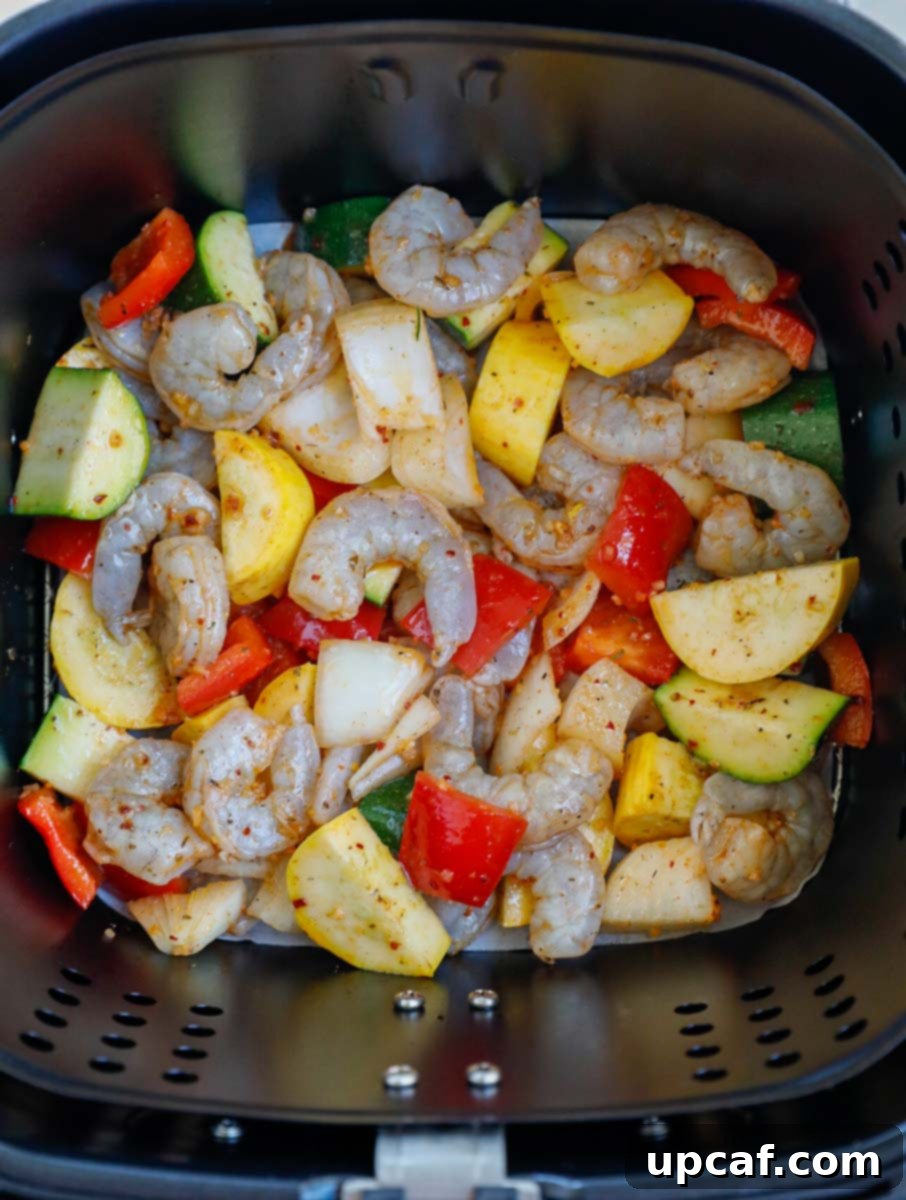 Raw marinated shrimp and mixed vegetables placed in an air fryer basket.