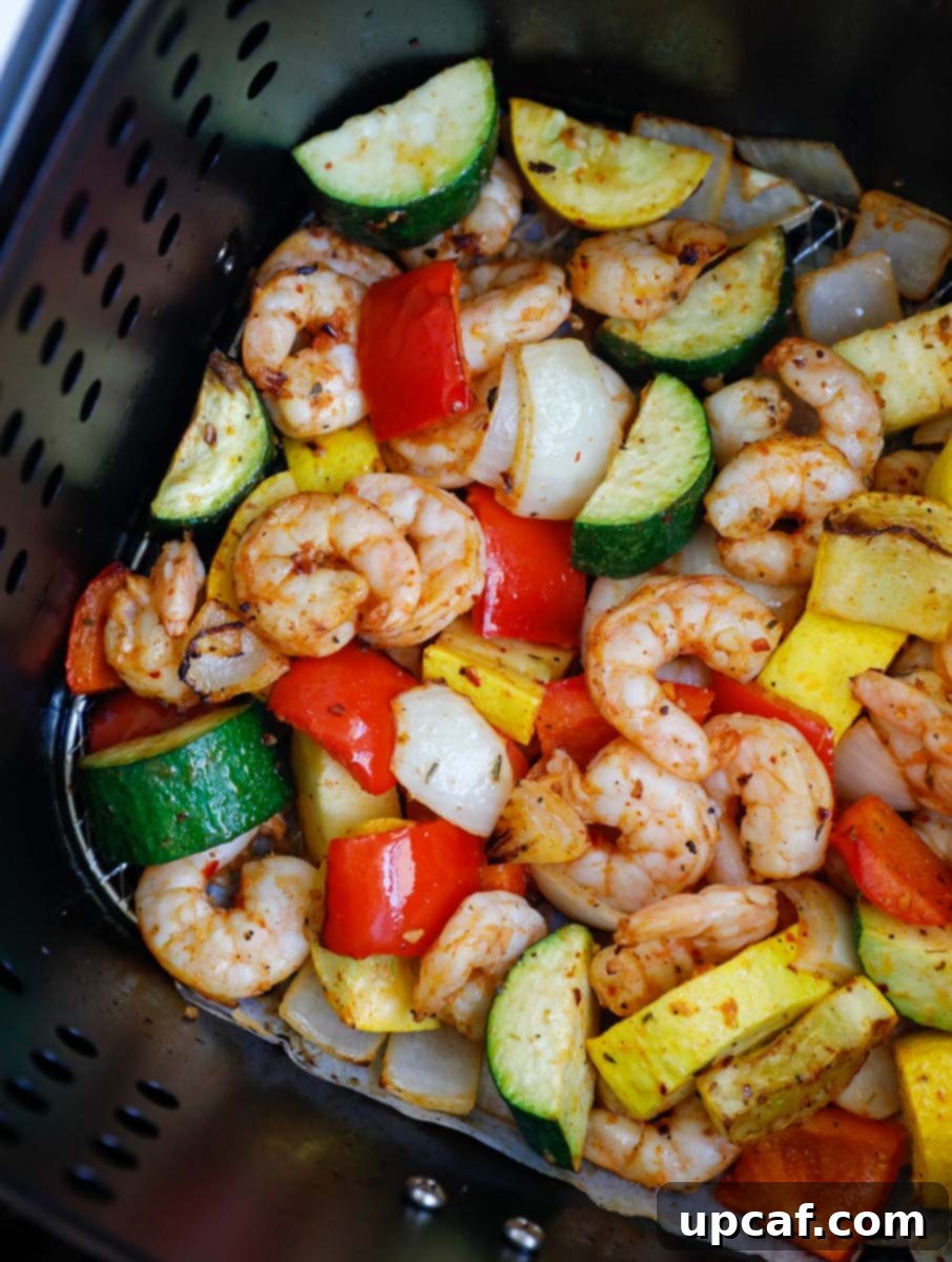 Perfectly cooked shrimp and vibrant vegetables glistening in the air fryer basket.