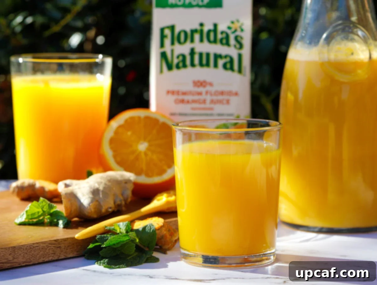 Freshly made orange juice immune booster drink outdoors, with a carton of Florida's Natural orange juice, ginger, and oranges in the background.