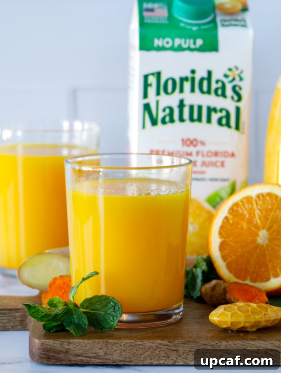 Close-up of the Orange-Ade Immune Booster Drink in a glass with a Florida's Natural orange juice carton visible in the soft background.