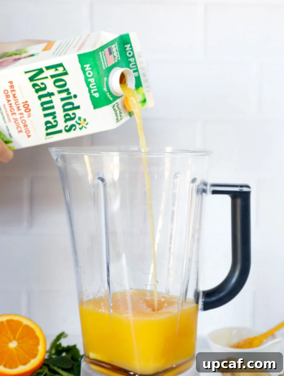 Ingredients for the immune booster drink in a blender with Florida's Natural orange juice being poured in.