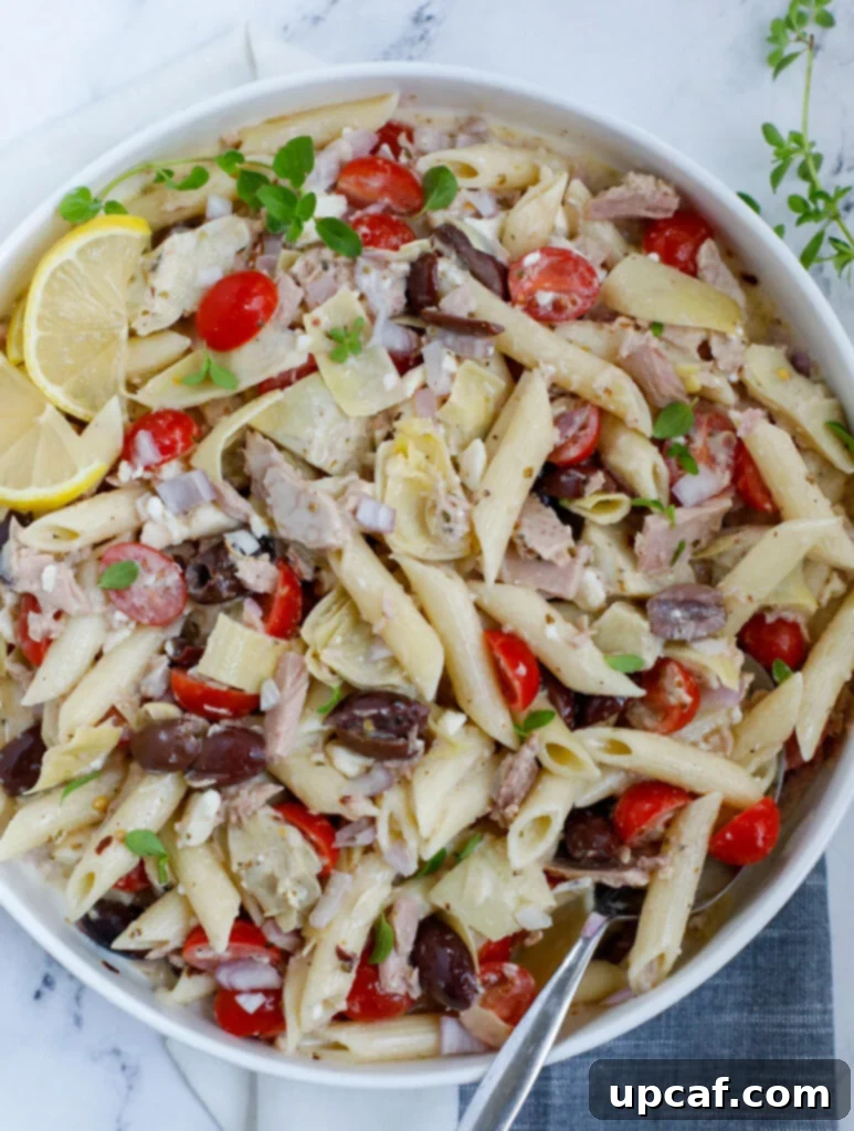 Top down shot of Greek Tuna Pasta Salad in a large serving bowl, garnished with fresh herbs.