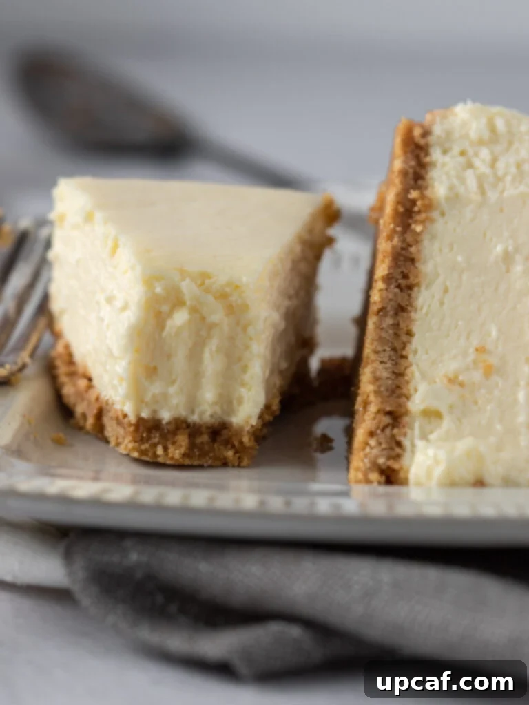 Close up of perfectly cut slices of New York style cheesecake on a white plate, showing the smooth texture.
