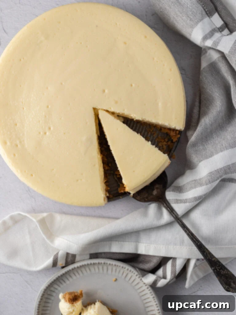 A whole New York style cheesecake with a slice being expertly cut out, highlighting its creamy interior.