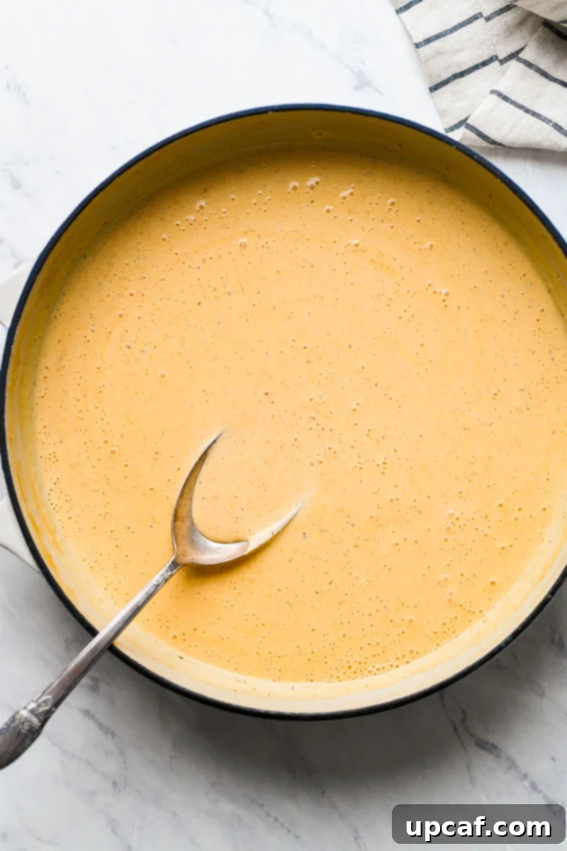 Rich and creamy Cajun cheese sauce simmering in a skillet.