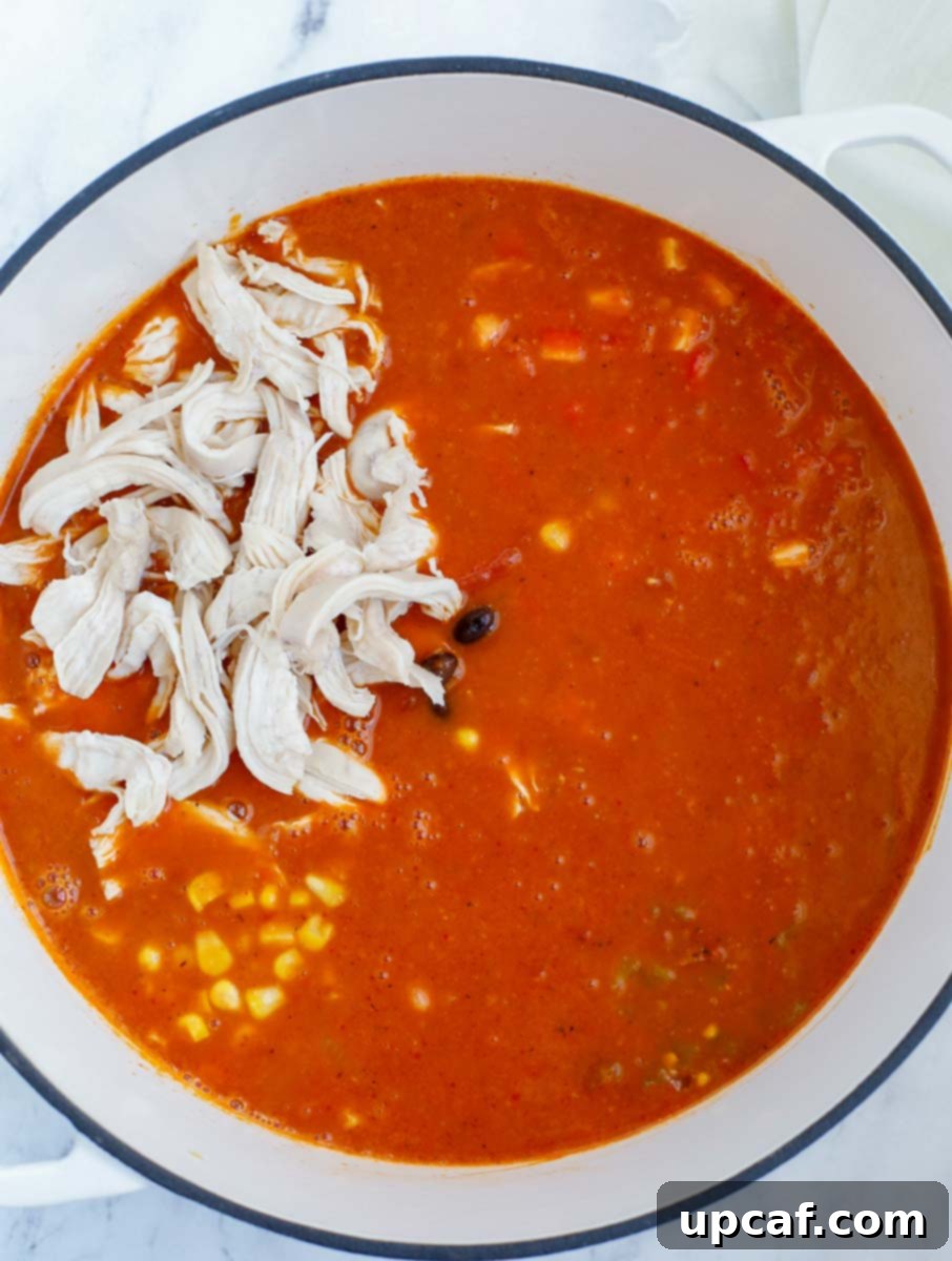 Adding shredded chicken, black beans, corn and green chilies into the pot.