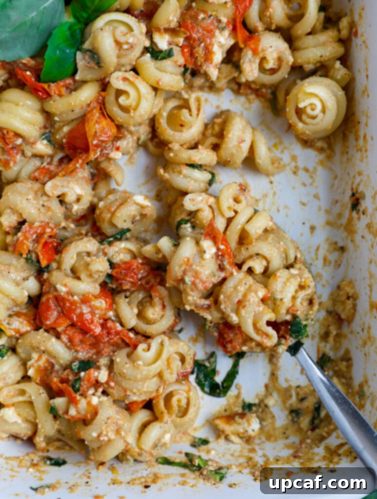 Golden Feta Pasta Bake 10 Feta pasta being spooned out of a white casserole dish.