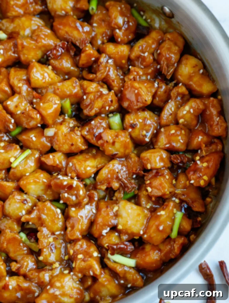 Close up of a skillet with bite-sized pieces of General Tso's chicken, coated in sauce.
