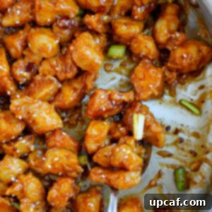Close up of a spoonful of crispy general tso chicken.
