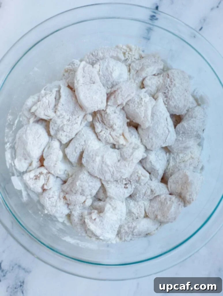 Chicken pieces being thoroughly covered in flour and seasoning mixture.