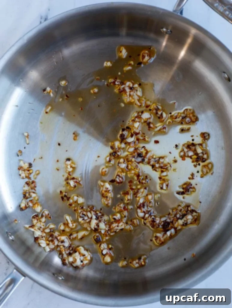 Image of sautéing minced garlic and chili flakes in a skillet.