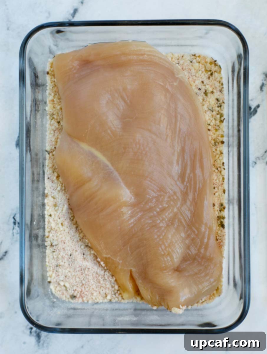 Chicken breast being added to the dry breading mixture for coating.