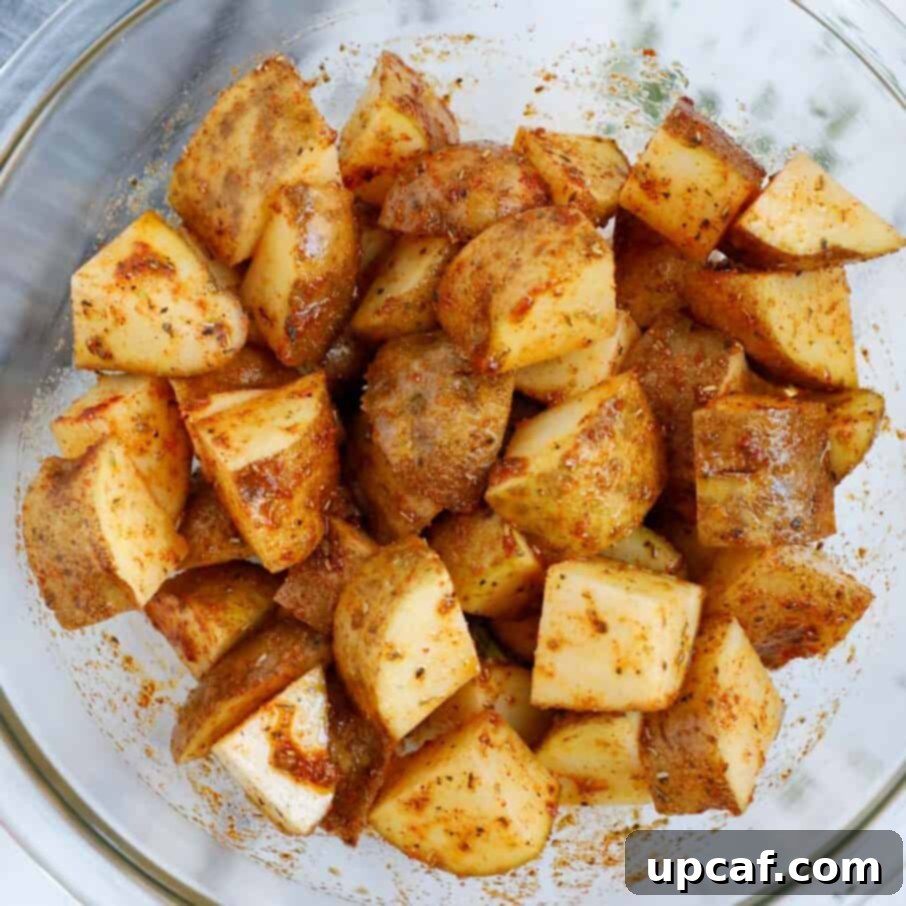 Seasoned potatoes in a bowl before air frying.