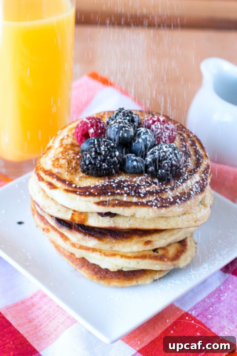 Blackberries, raspberries, and blueberries on top of a stack of pancakes