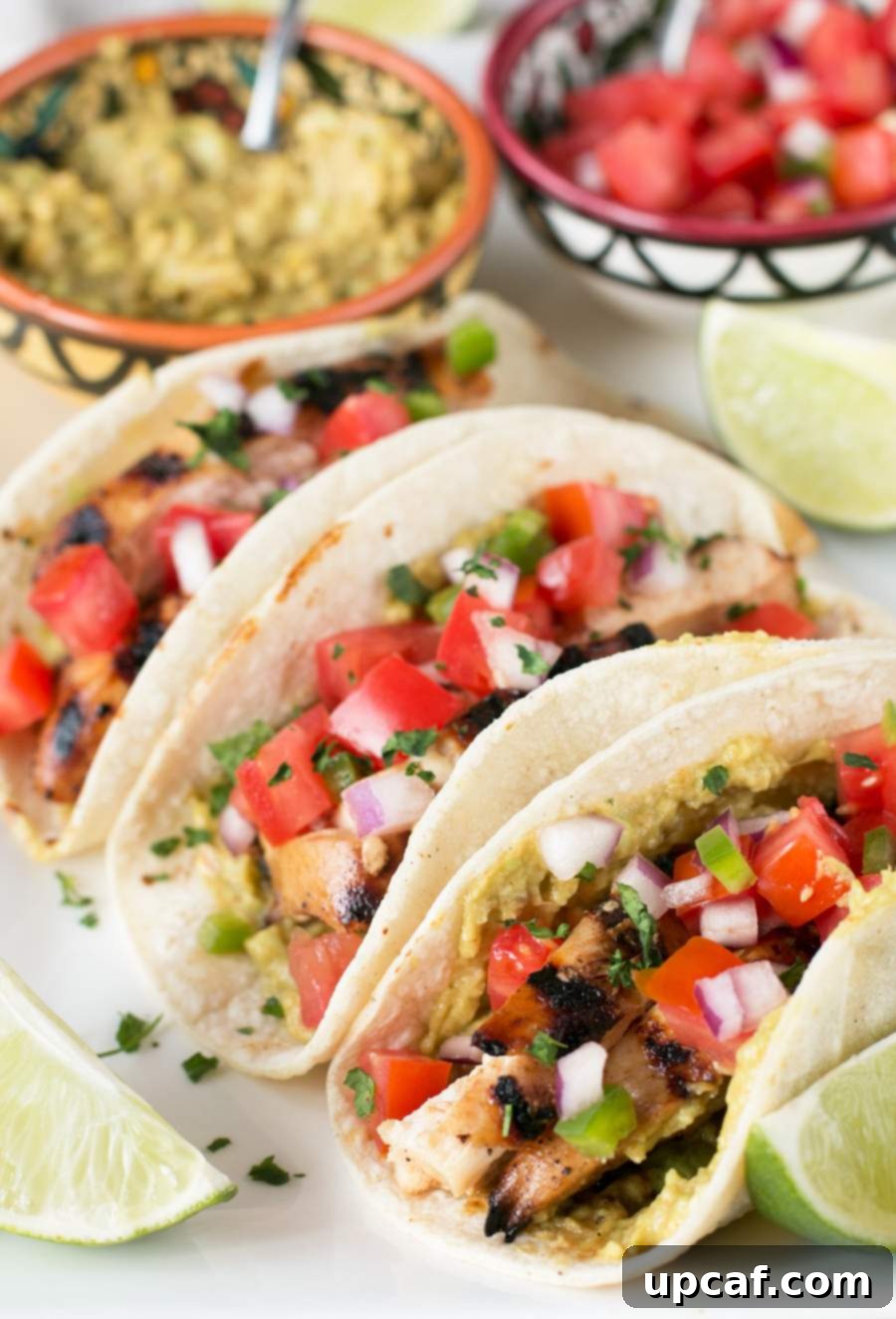 Fiesta Chicken Tacos 4 Three perfectly assembled Mexican Chicken Tacos arranged on a white plate in soft corn tortillas, ready to be enjoyed.