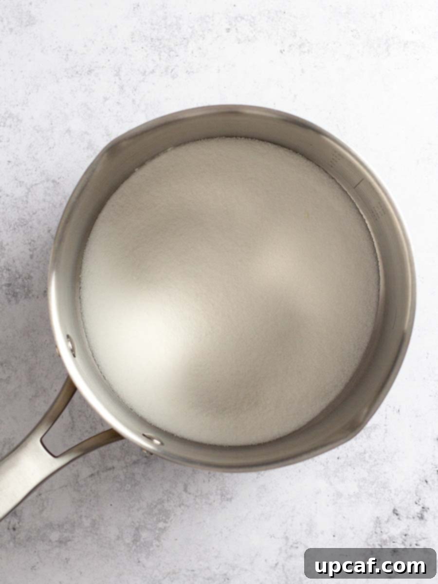 A wide saucepan with an even layer of white granulated sugar at the bottom, before cooking begins.