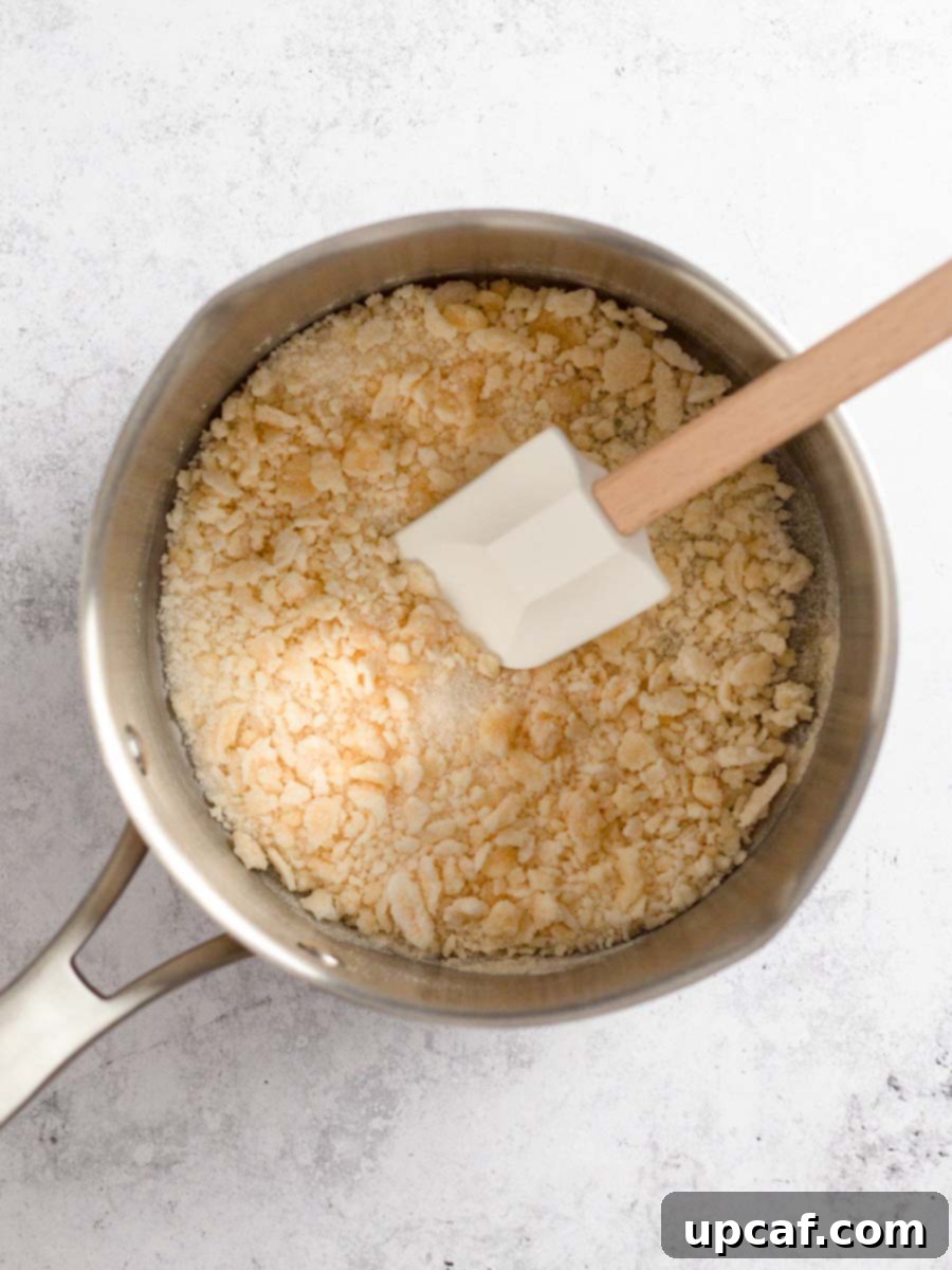 As the sugar cooks, it begins to form golden clumps and some liquid, indicating the start of the caramelization process.