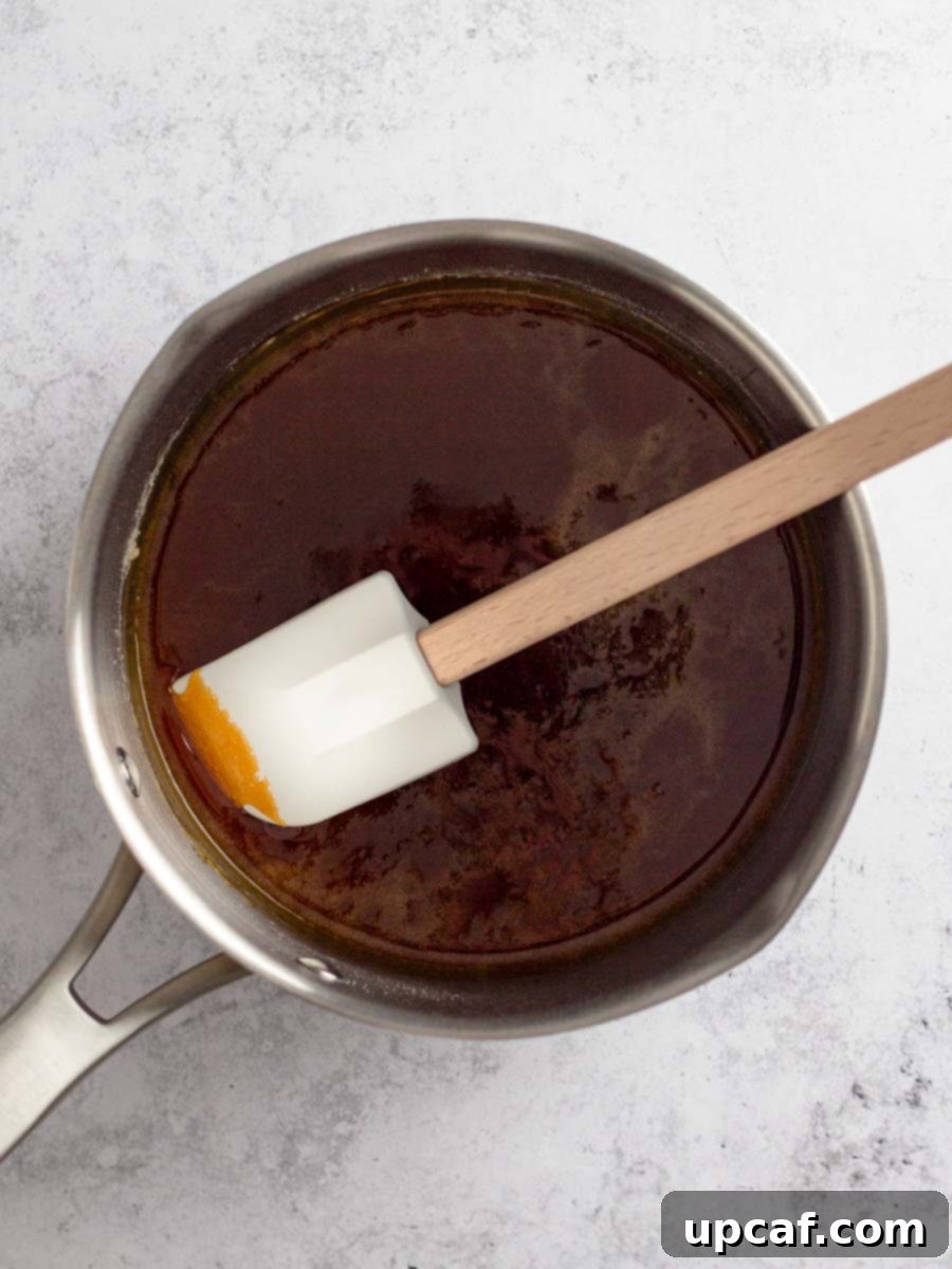 The fully caramelized sugar in the saucepan, now a deep amber or copper color, indicating it's ready for the next step.