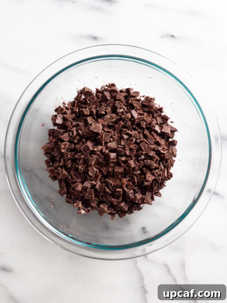 Finely chopped semi-sweet chocolate pieces neatly arranged in a glass bowl, ready for melting.