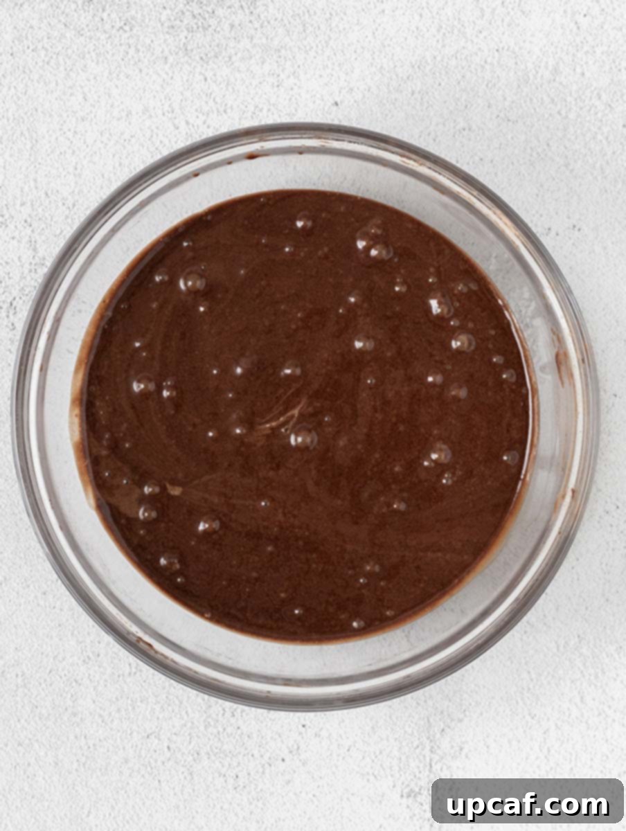 Smooth chocolate cupcake batter in a large mixing bowl, ready for baking.