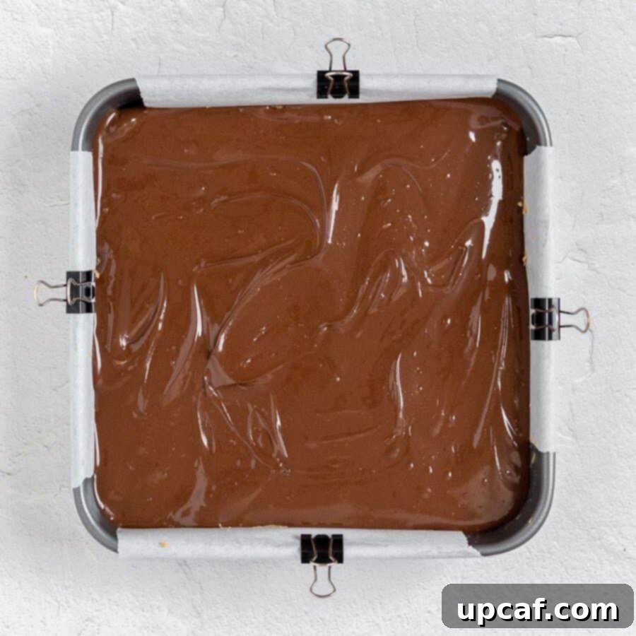 The assembled chocolate peanut butter oatmeal bars in a square pan before chilling.