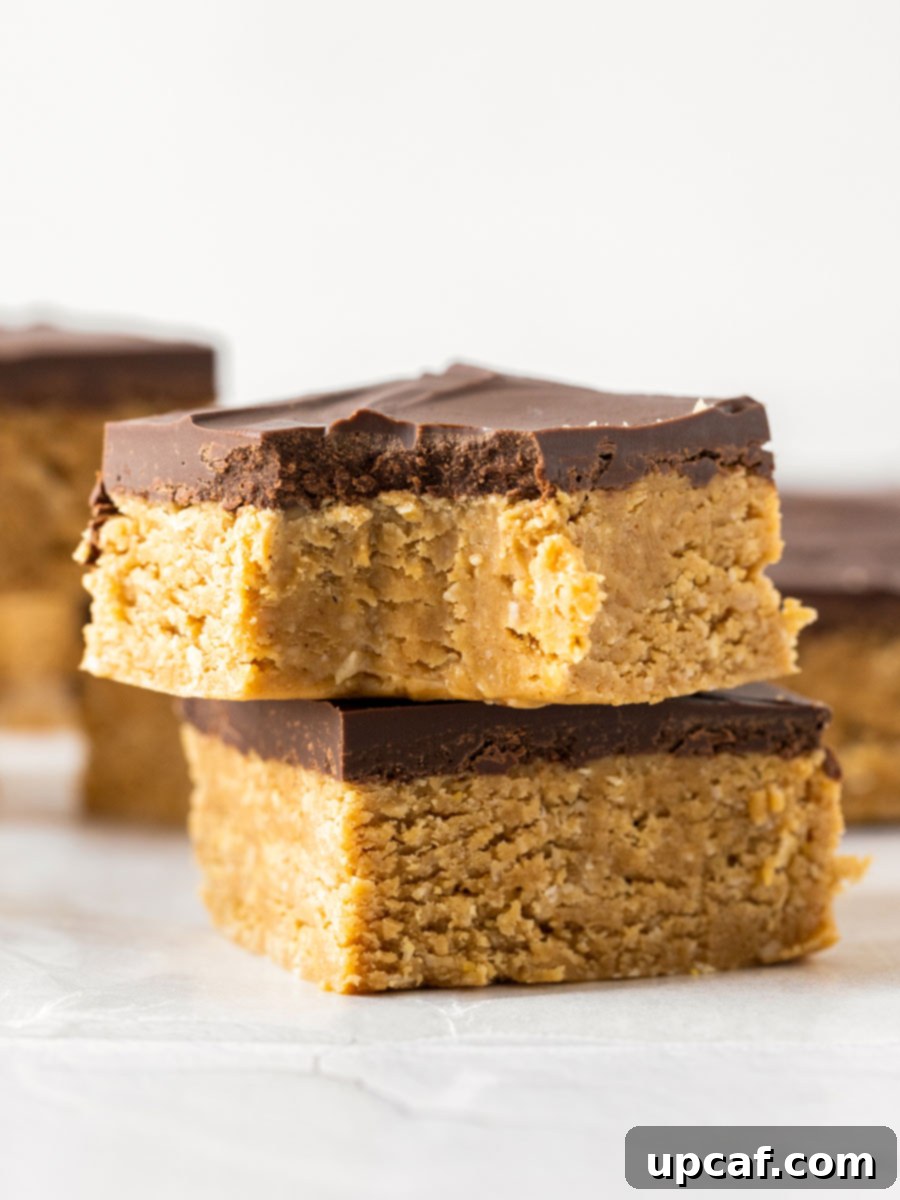 Two chocolate peanut butter oatmeal bars stacked on top of each other, showcasing their layers.