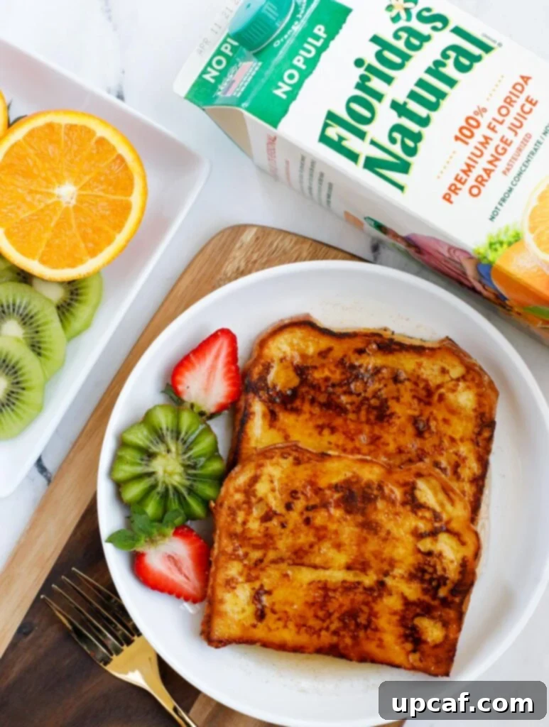 Ultimate Orange French Toast 2 A plate of golden-brown orange French toast, perfectly cooked and ready to be enjoyed, garnished with fresh fruit.