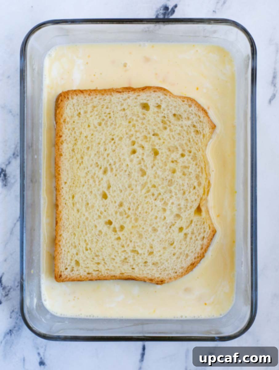 Ultimate Orange French Toast 5 Soaking a slice of bread in the custard.