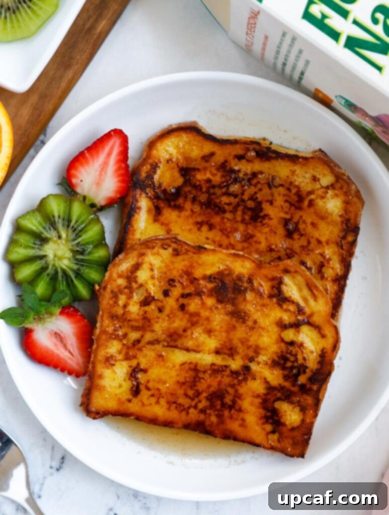 Ultimate Orange French Toast 8 Orange french toast on a plate served with a kiwi and sliced strawberry, garnished with fresh mint.