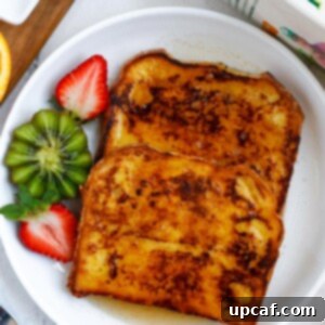 Ultimate Orange French Toast 9 Orange french toast on a plate served with a kiwi and sliced strawberry.