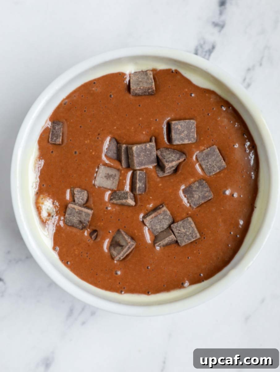 Chocolate Peanut Butter Banana Oatmeal Bake 7 Chocolate peanut butter baked oats batter in a ramekin with chocolate chunks on top.