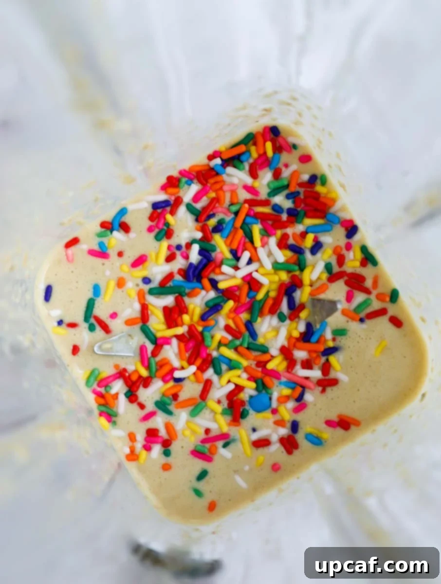 Batter being mixed with sprinkles in a blender, showing the colorful specks.