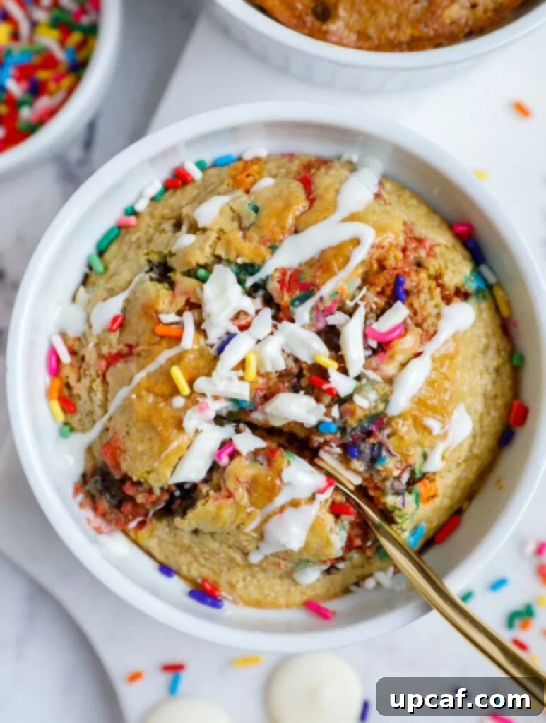 Baked funfetti baked oats with frosting and a spoon, highlighting its cake-like texture.