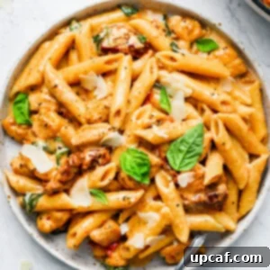 A plate of creamy sun-dried tomato pasta with fresh basil and parmesan shavings on top.
