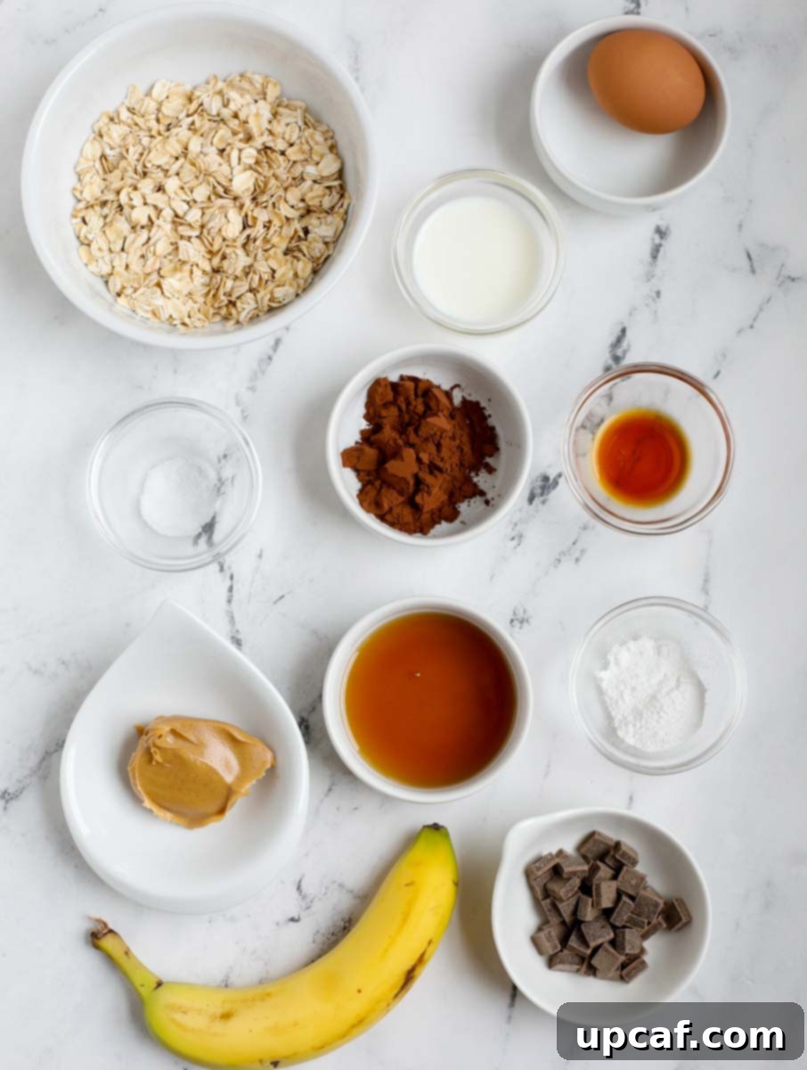 Baked Oats Reimagined Three Delicious Versions 5 Ingredients required for peanut butter chocolate oats cake, showing oats, banana, peanut butter, cocoa powder, chocolate chips, egg, milk, maple syrup, and vanilla.