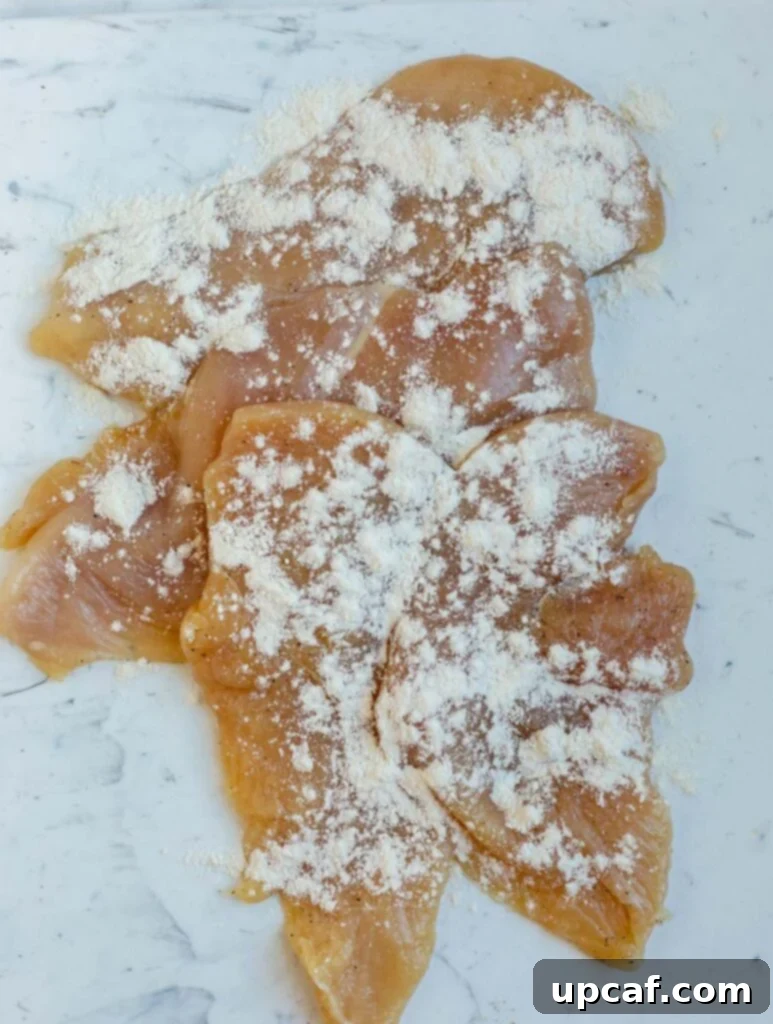 Coating chicken breasts with flour.