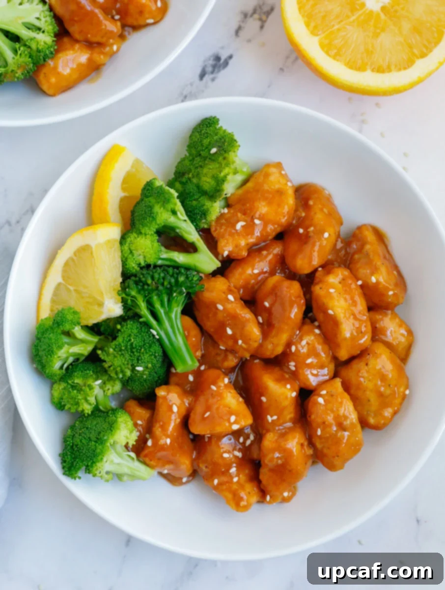 Wholesome Orange Chicken 2 A plate of healthy orange chicken with steamed broccoli and fresh lemon wedges, ready to be served.
